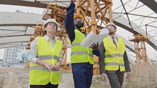 Construction Workers Review Plans at Building Site