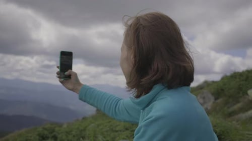 Woman Photographs Mountain Scenery with Smartphone