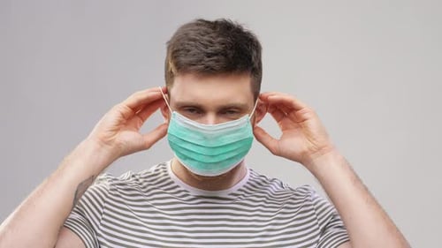Young Adult Putting on a Surgical Mask