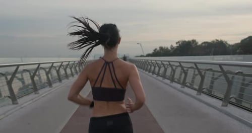 Fit Female in Sportswear Running on Modern Bridge During Fitness Training in Evening in City