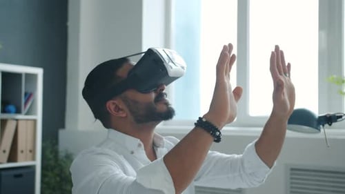 Smiling African American Man Wearing Virtual Reality Glasses Moving Arms in Office