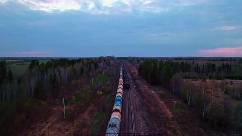 Freight Train Transporting Cargo Across Forest Landscape at Dusk