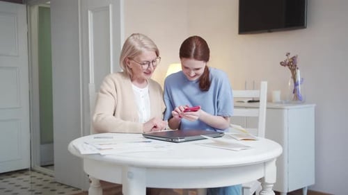 A Pensioner with Glasses and Her Adult Daughter Look at Photos on the Phone Comment and Discuss