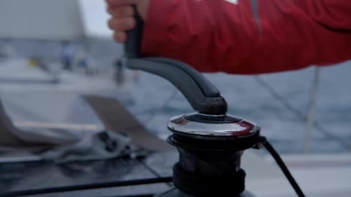Closeup up of Yachtsman hands pulling rope on sailboat, yacht detail, working on water transport
