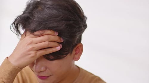 Distraught Young Adult with Headache Holds Head