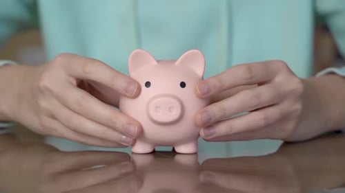 Female hands putting a piggy bank on the table. Money saving concept.