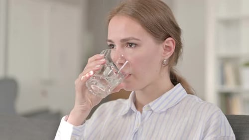 Junge Frau trinkt Wasser und nimmt einen Schluck
