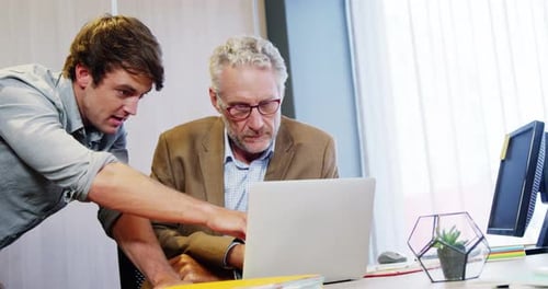 Two Colleagues Collaborating on Laptop in Office