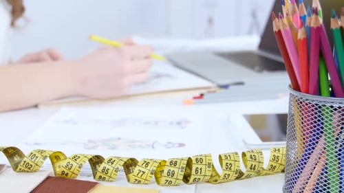 Fashion Designer Draws Sketches for a New Collection and Smiles Sweetly. Close Up