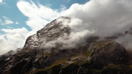 High Dolomite peak in northern Italy with rocky cloudy top during a clear winter day, Aerial drone d