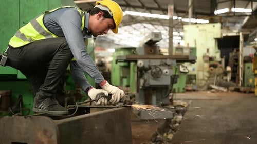 Asiatische Techniker arbeiten in einer mechanischen Fabrik. Verwenden Sie eine Stahlschleifmaschine, um alte Maschinenteile zu bauen.