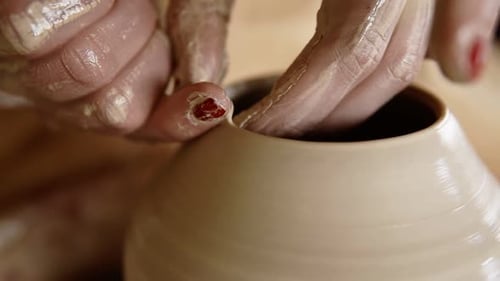 Mains de potier mouillées et habiles façonnant l'argile sur un tour de potier et sculptant un vase à l'aide des doigts