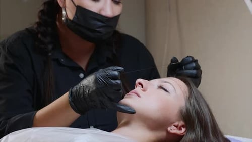 Ein Microblading-Meister misst die Augenbrauen von Frauen