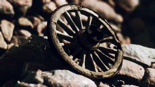 Weathered Wooden Wheel Resting on Sunlit Rocks