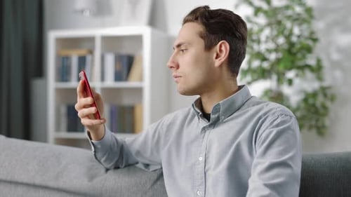 Young Adult Using Smartphone While Relaxing on Sofa