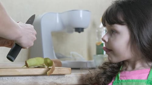 Woman Peels Kiwi as Child Watches