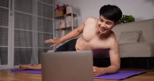 Young Man Exercising with Laptop in Living Room