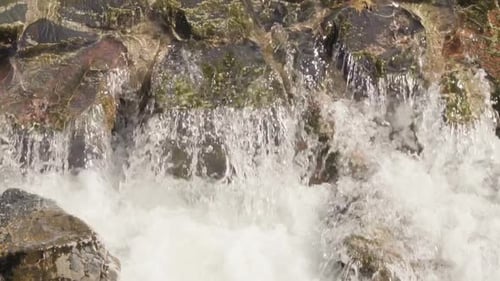 Slow motion. Small waterfall in urban park during Autumn.