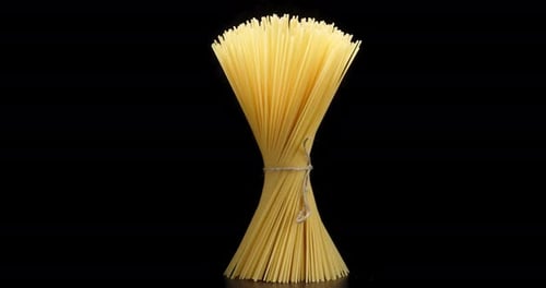 Bundle of Uncooked Spaghetti Standing on Black Surface
