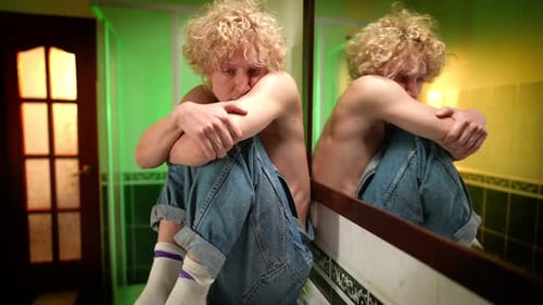 Young Adult Sitting Thoughtfully in Bathroom