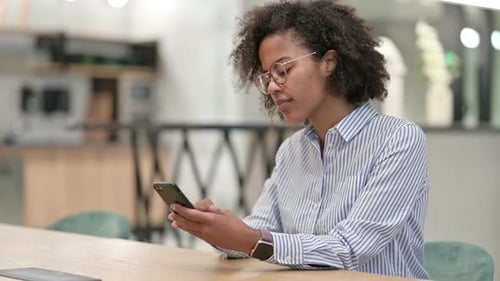 Serious African Businesswoman Using Smartphone in Office