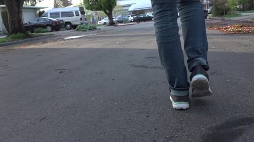 Person Walking on Suburban Street Towards the Camera
