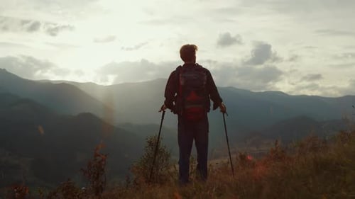 Lone Hiker Reaches Mountain Peak at Sunset