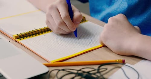 Shot of Young Boy's Hands Drawing Circles Diagrams on Paper in Notebook Child Creates Notes for