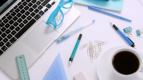 Laptop, spectacles, pen, coffee, paper clip, scale, set square and headphones on white background 4k