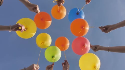 Colorful Balloons Held Up to a Bright Blue Sky