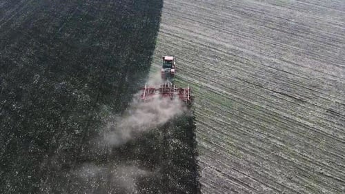 A Red Tractor Plows the Ground. Drone Point of View. The Concept of Land Cultivation and