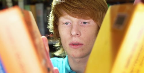 Young Adult Searching Through Books in Library