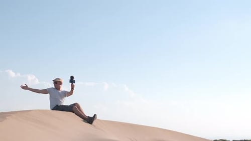 Man filming himself with his cell phone in the desert dunes.