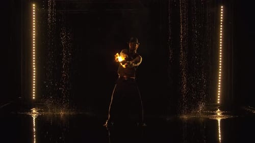 Fire Juggler Performing in Dark, Wet Environment