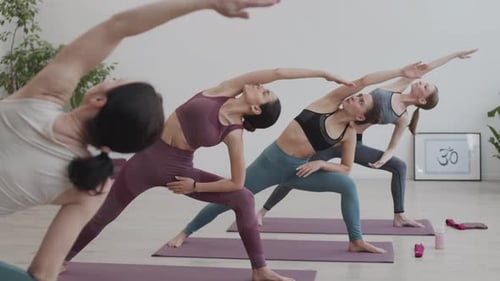Women Practicing Yoga Poses in Bright Studio
