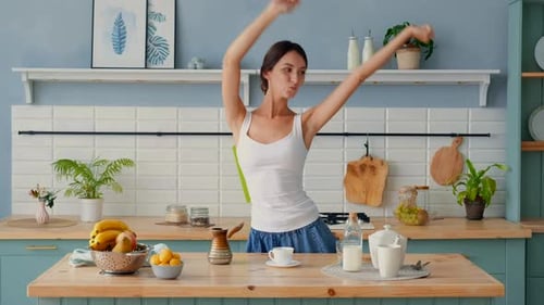 Carefree Woman Dances in Kitchen with Pear