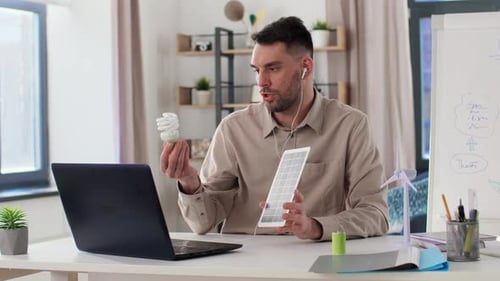 Profesor masculino con portátil y batería solar en casa