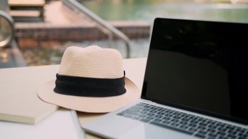 summer travel concept laptop summer hat and paper note book arrange on pool bench