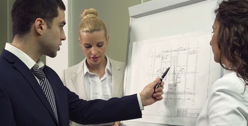 Business Colleagues Reviewing Blueprints at Workplace