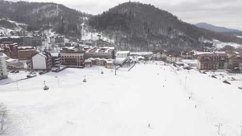 Luftaufnahme des Skigebiets mit verschneiten Berghängen und Winterbäumen.