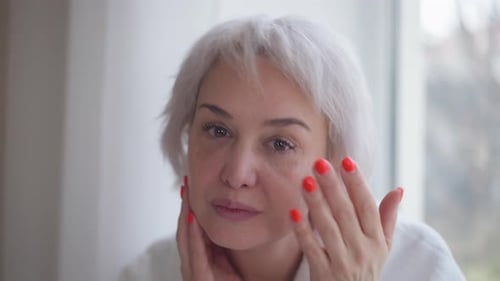 Front View Face of Mature Woman Examining Wrinkles Looking at Camera