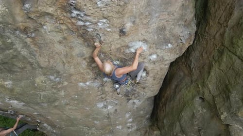Determined Senior Woman Climber Clambering Up Steep Wall of Rocky Mountain