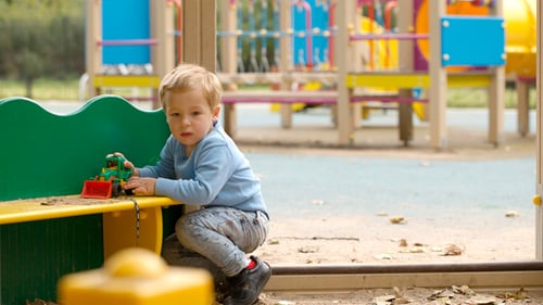 Young Child Playing with a Toy Tractor in Sand