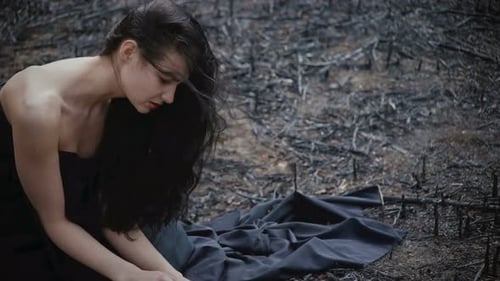 Solitary Woman Kneeling on Burned Ground