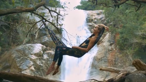 Woman Relaxing in Hammock near Tropical Waterfall