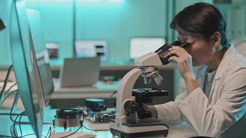 Asian Female Engineer Using Microscope in Lab