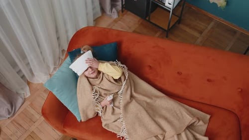 Child Lying on Couch with Cloth on Head