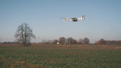 White Drone Flying on Nature Background. Drone Hanging in Air Flying Helicopter Dron Remote Control
