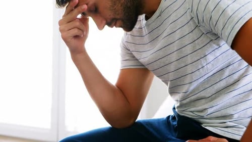 Worried man sitting on bed in the bedroom