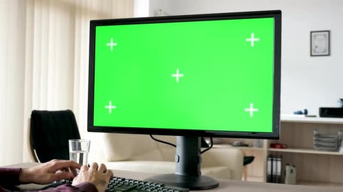 Unrecognisable Man Typing on Personal Computer Keyboard with Big Green Screen Chroma Mockup